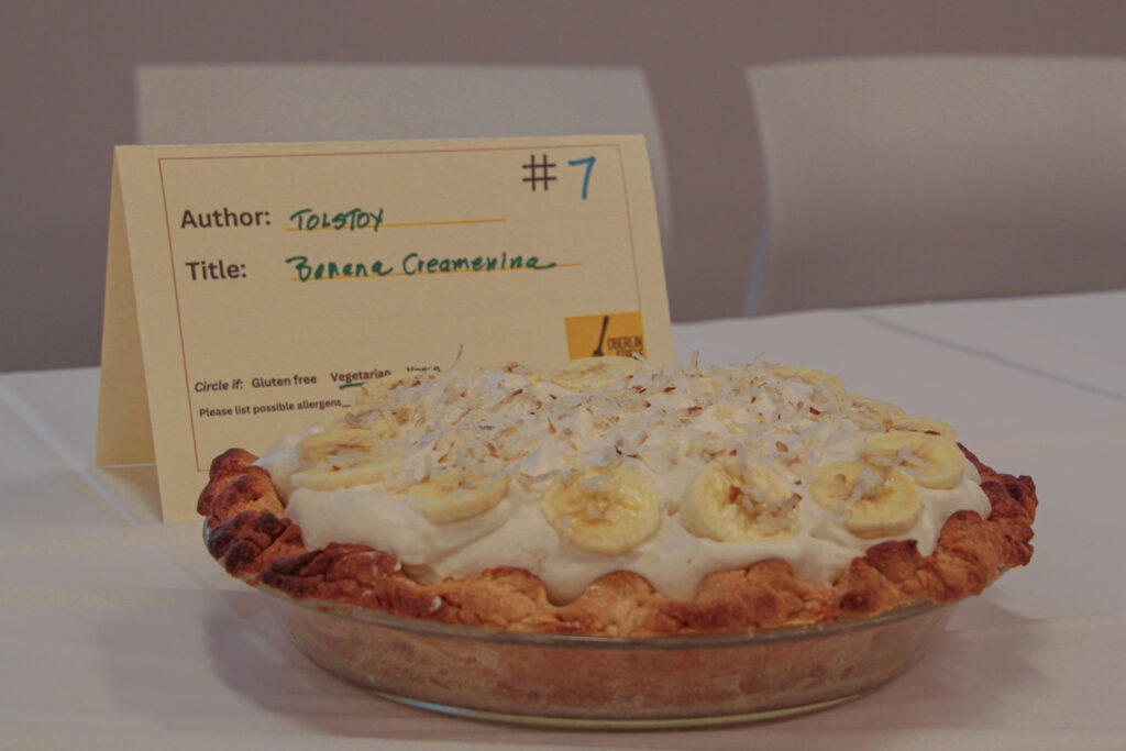 Pie with cream, bananas arranged in a circle, and coconut shavings on top.