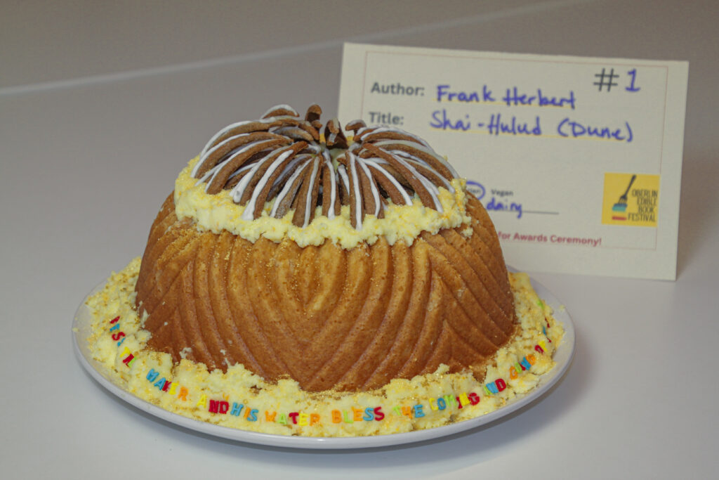 Light brown circular cake with yellow and brown details to depict sandworm from book.