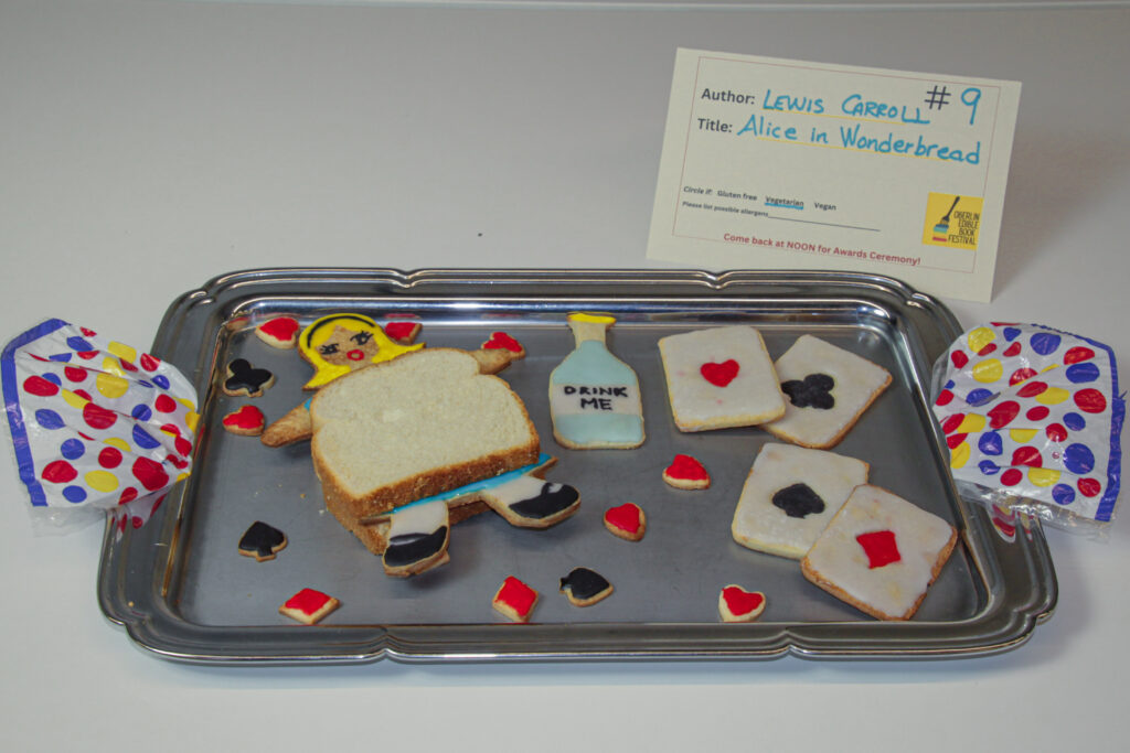 Tray with cookies resembling playing cards and a bottle, and an Alice cookie sandwiched between two slices of bread.