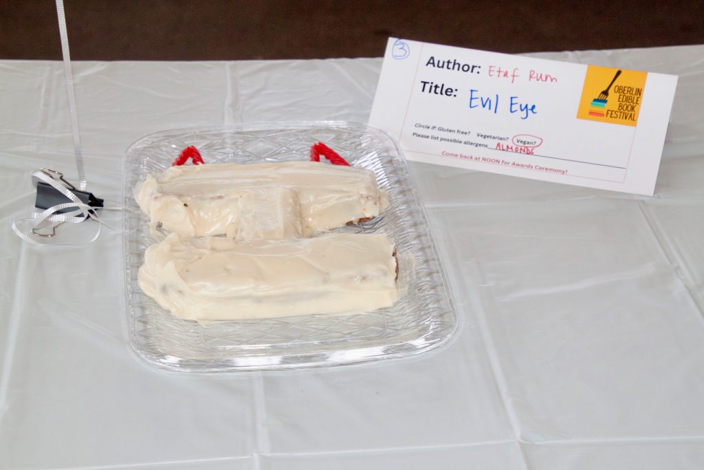 Photo of submission titled, "Evil Eye" featuring a cake in the shape of the letter "I" and two Twizzler candies representing devil horns