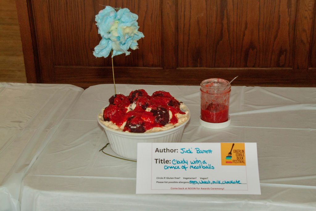 Photo of submission titled, "Cloudy with a Chance of Meatballs" featuring a dish of meatballs with a cloud made of cotton candy suspended above it in a wire and a small jar of marinara sauce to the side