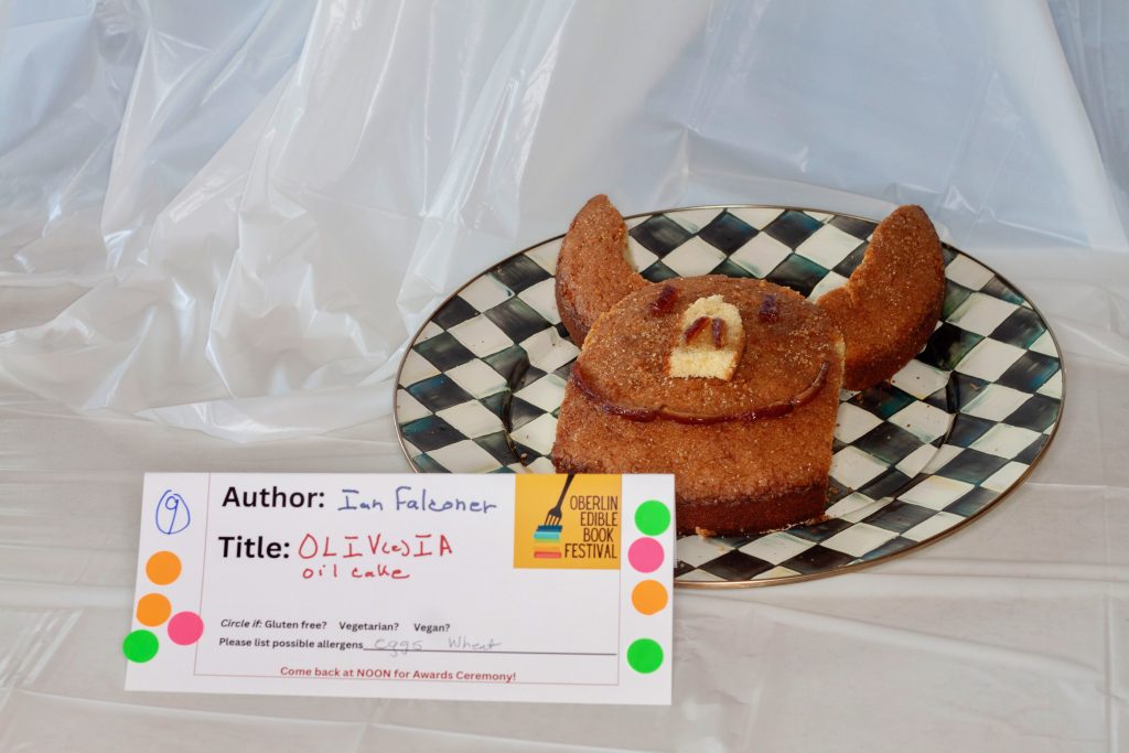 Photo of submission titled, "Oliv(e)ia Oil Cake" featuring a cake in the shape of a smiling pig face